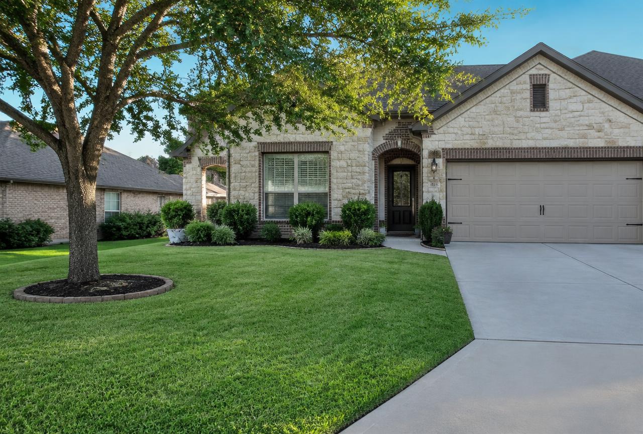 Freshly mowed and edged Austin residential lawn with clean bed edges, trimmed shrubs and a clear driveway edge